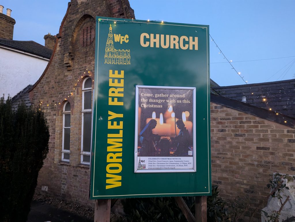 Christmas lights and poster at church as daylight begins to fade.